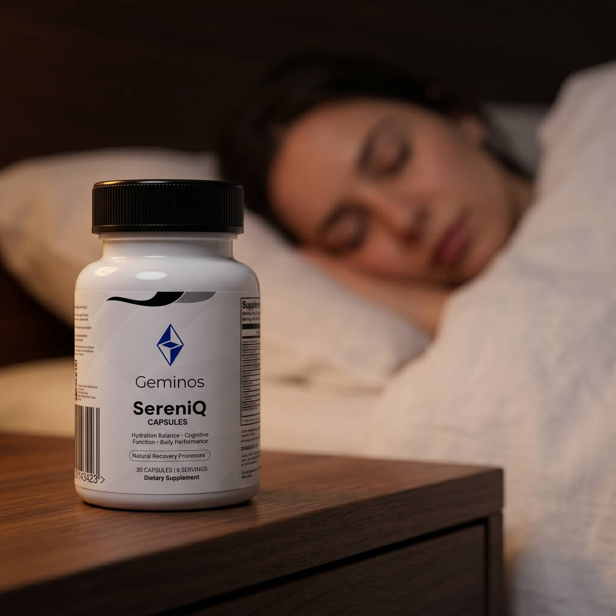 Bottle of Geminos SereniQ capsules on a nightstand with a person sleeping in the background.
